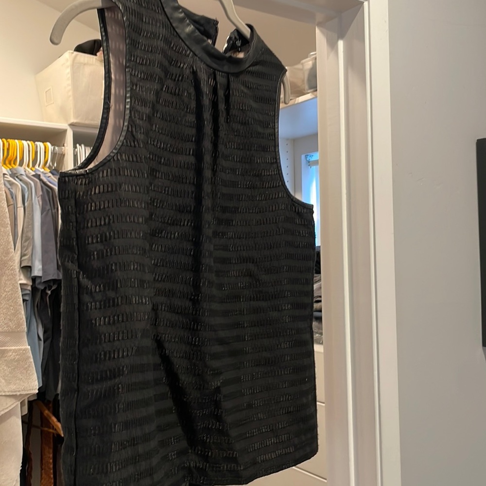 Sleeveless black blouse with leather trim. Toni